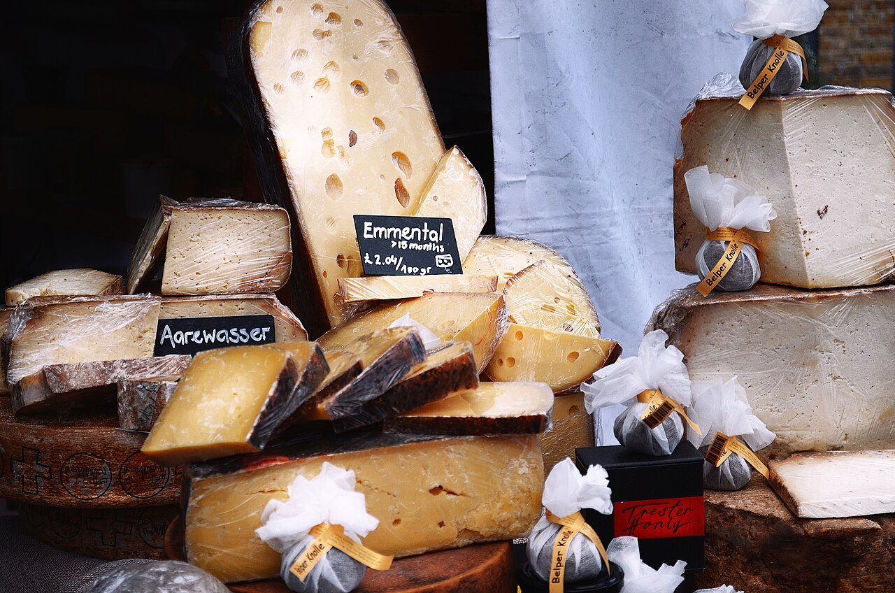 Round cheeses and wedges set out with handwritten price labels at a Borough Market stall