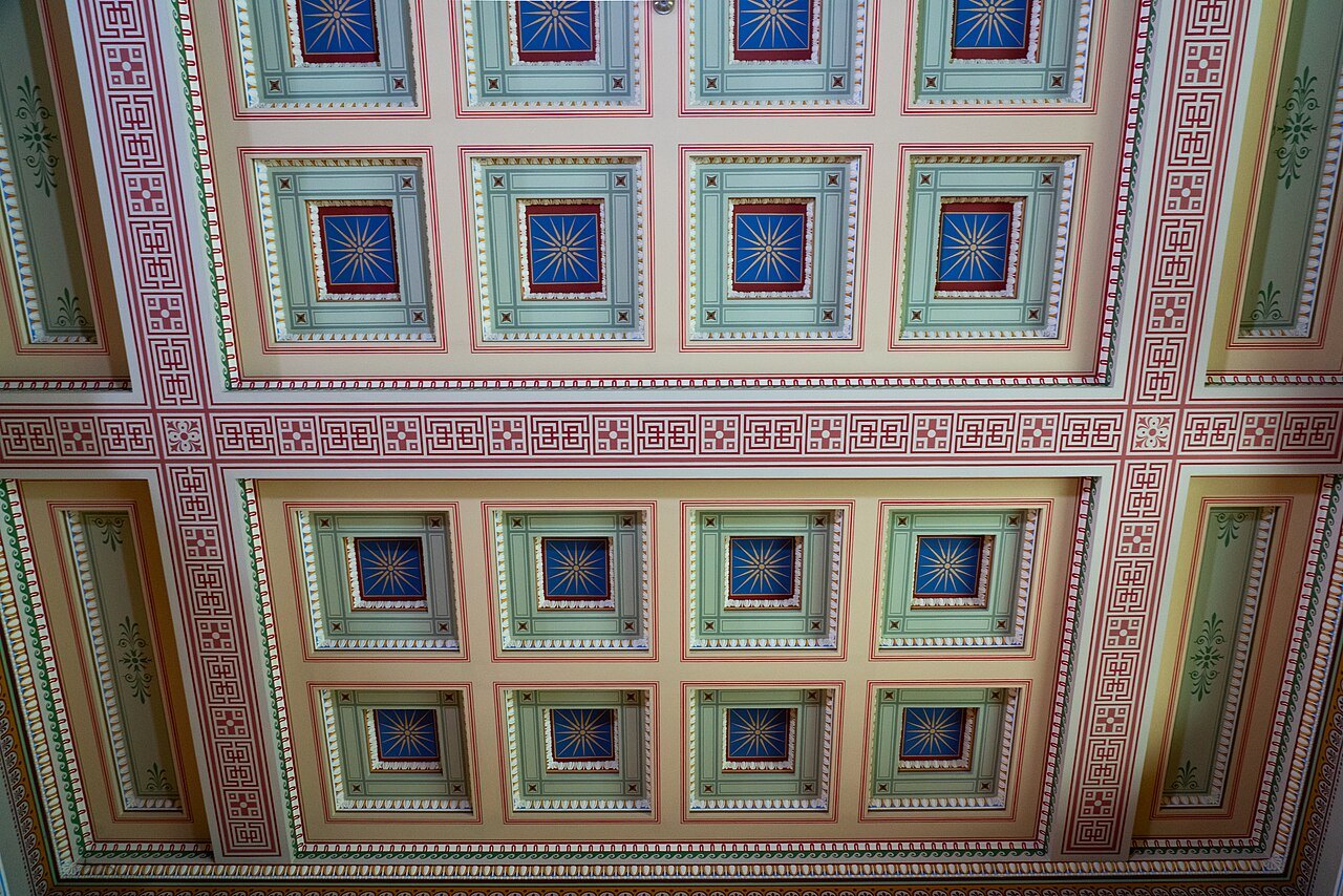 The painted and panelled ceiling of a gallery in the British Museum, in pink, green and blue