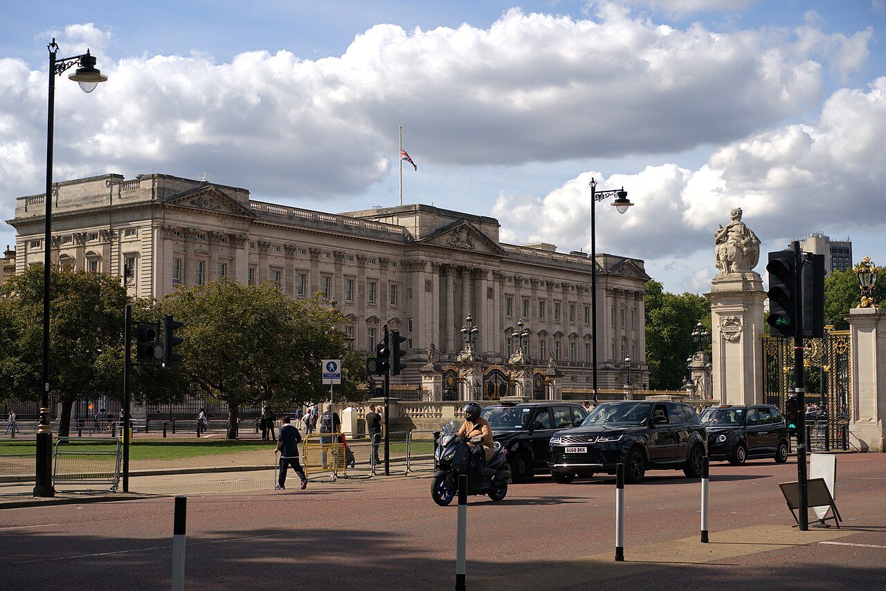 Buckingham Palace seen across the traffic at the roundabout, with the Victoria Memorial at the right