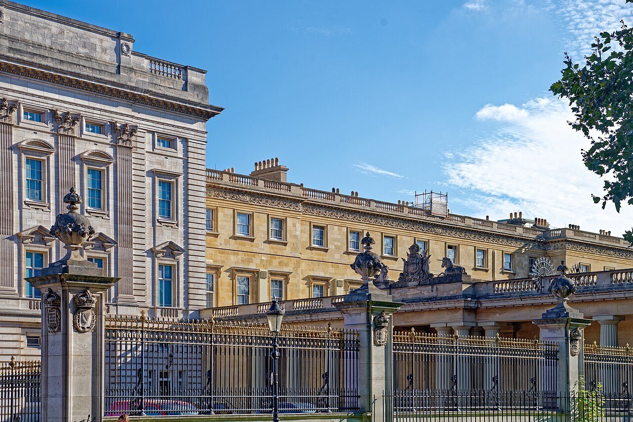 The railings and the gilded gateposts in front of Buckingham Palace, with the palace's side wing behind