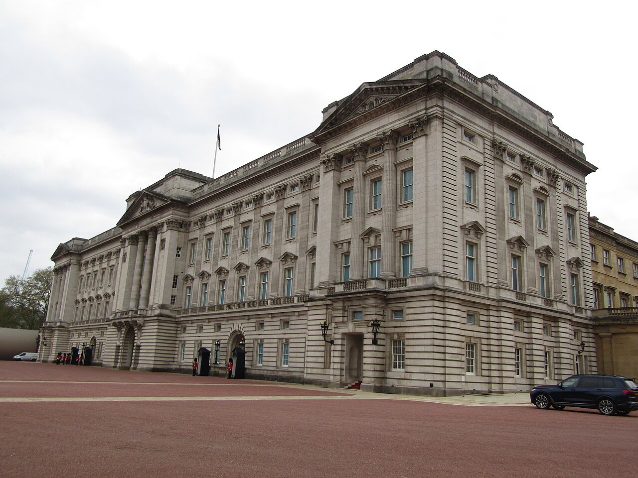 Buckingham Palace seen from the corner of its forecourt, a long classical block of pale stone