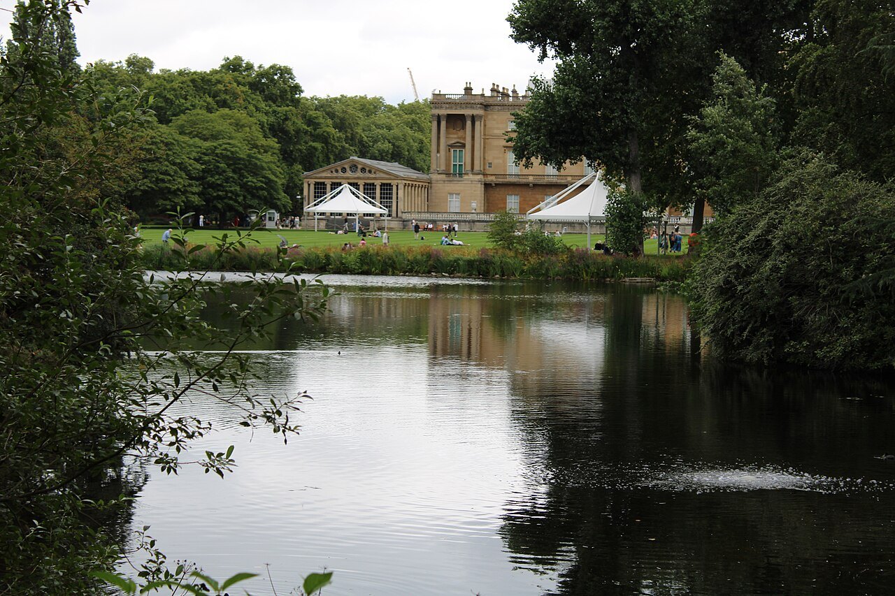 A still lake in St James's Park, with the back of Buckingham Palace showing through the trees