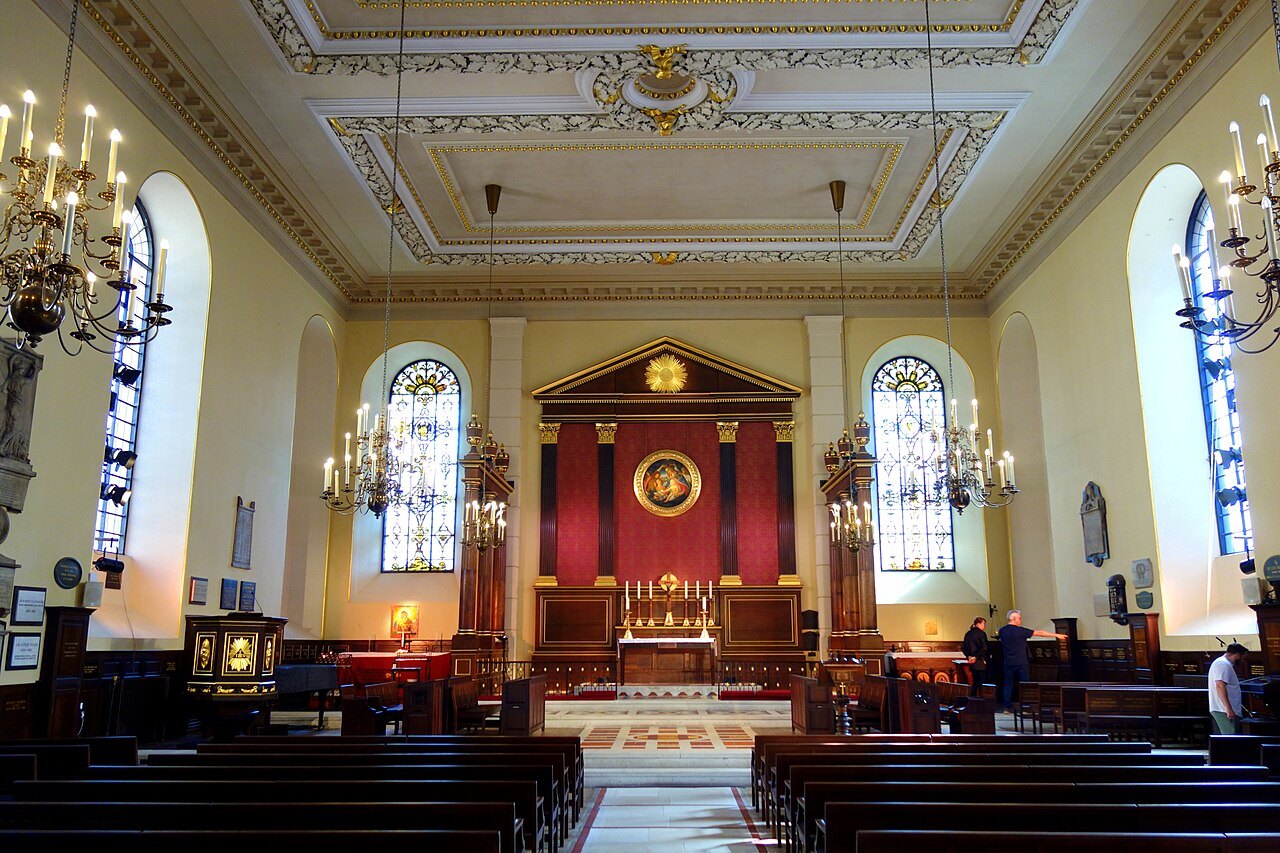 The interior of St Paul's Church in Covent Garden, with a red and gold altar under a plaster ceiling