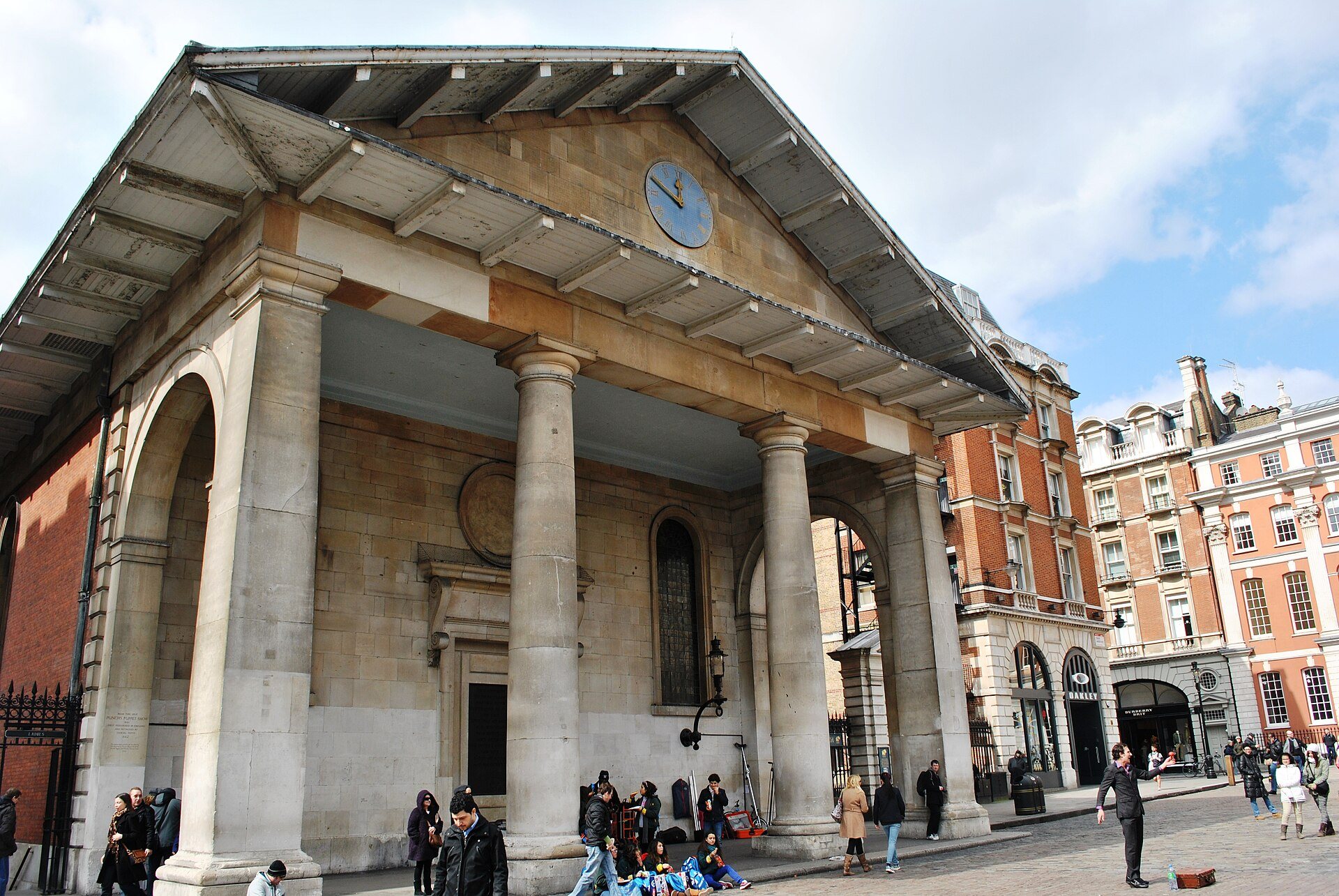 The portico of St Paul's Church in Covent Garden, its pillars facing the piazza, with red brick houses beside it