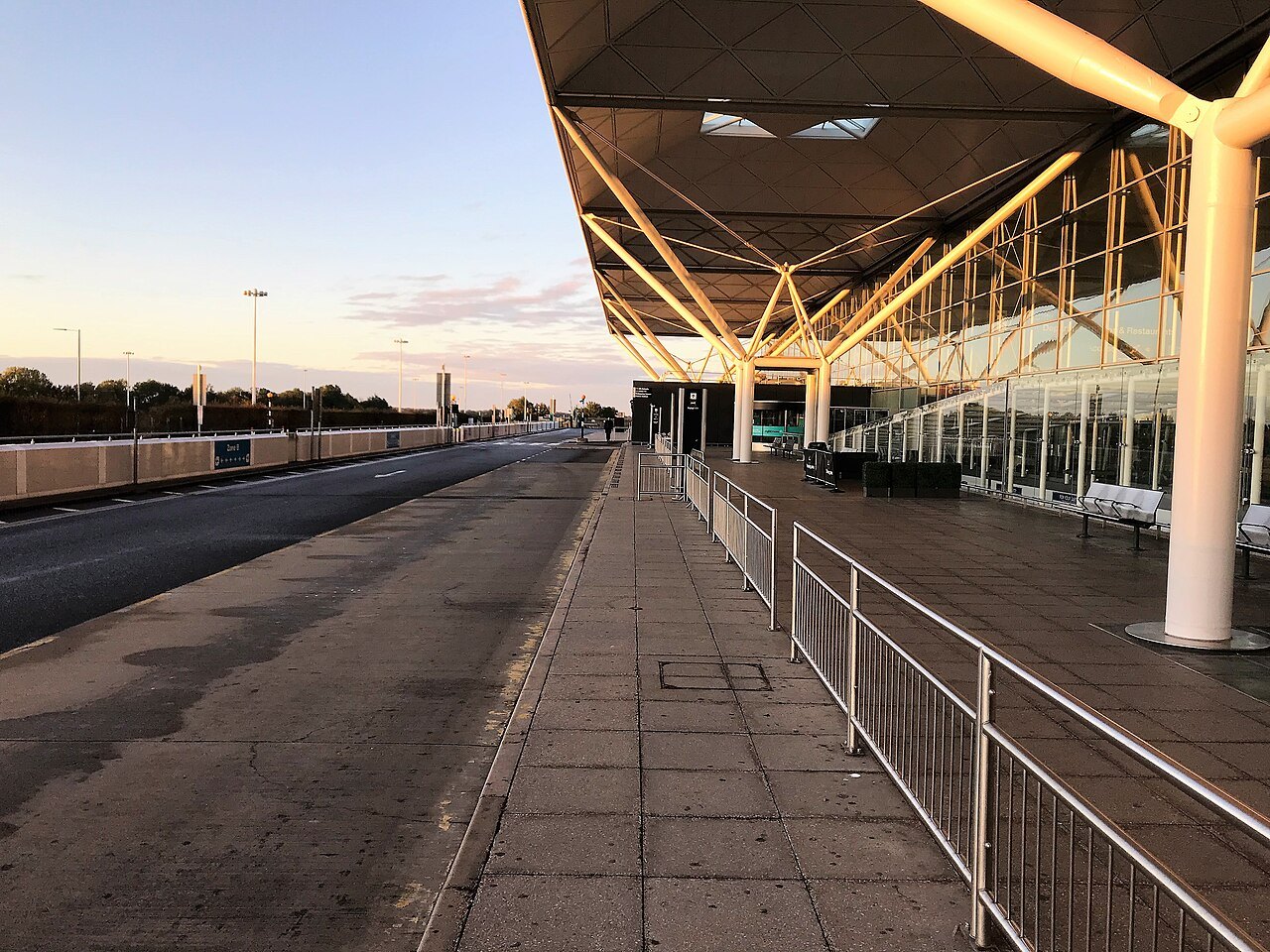 A deserted stretch of pavement outside Stansted Airport's terminal, with a canopy overhead