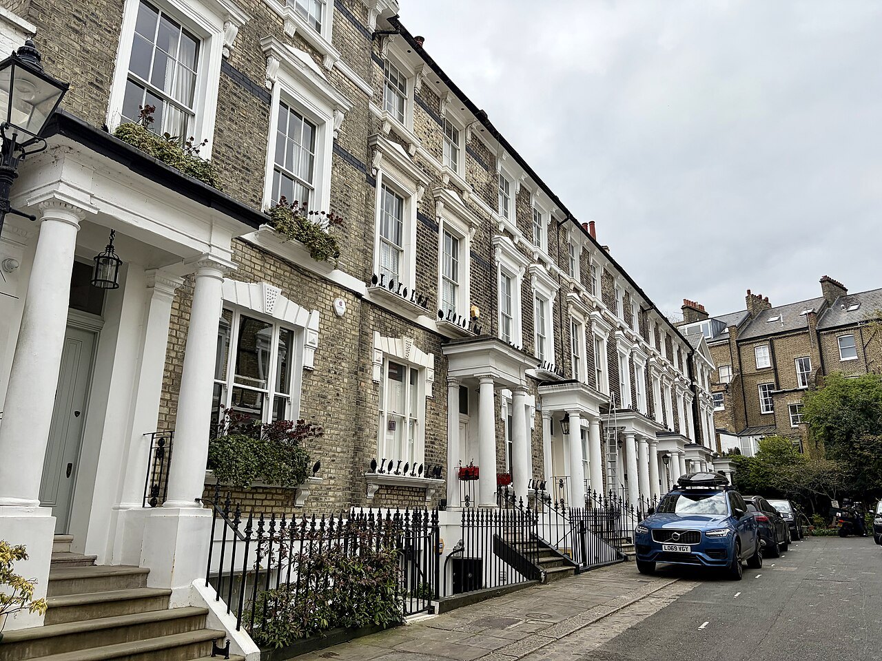 A terrace of white stucco houses along a quiet street in Primrose Hill