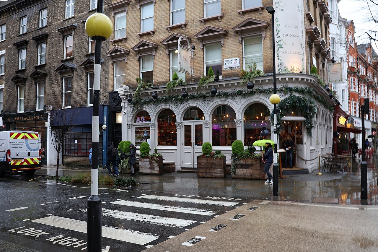 A pub-lined street corner on Marylebone High Street on a wet day, with a zebra crossing in front