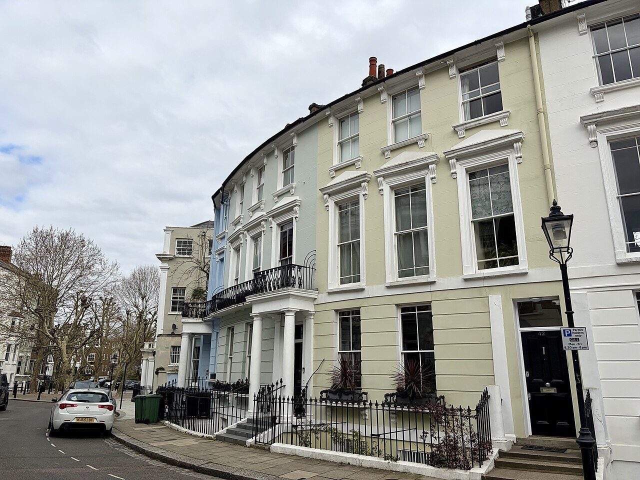 A curved terrace of cream stucco houses on a corner in Primrose Hill