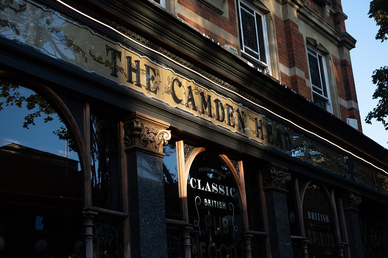 The gilded sign of the Camden Head, a Victorian pub in Islington, in dark glass and brass