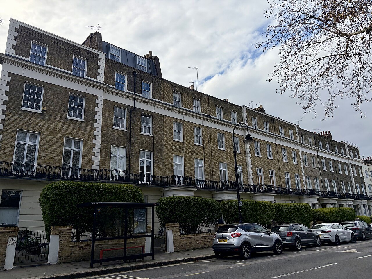 A long terrace of brick houses with railings and a bus stop in Primrose Hill