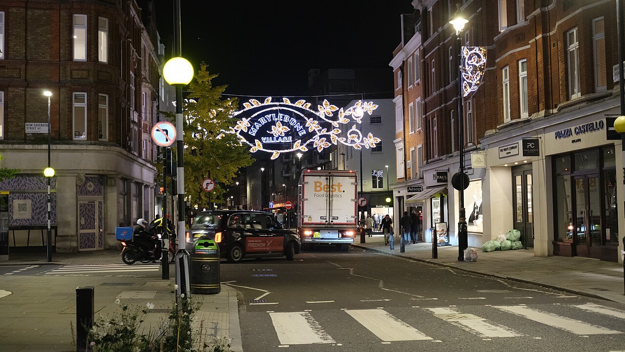 Marylebone High Street at night, with Christmas lights strung across the road and shops at either side