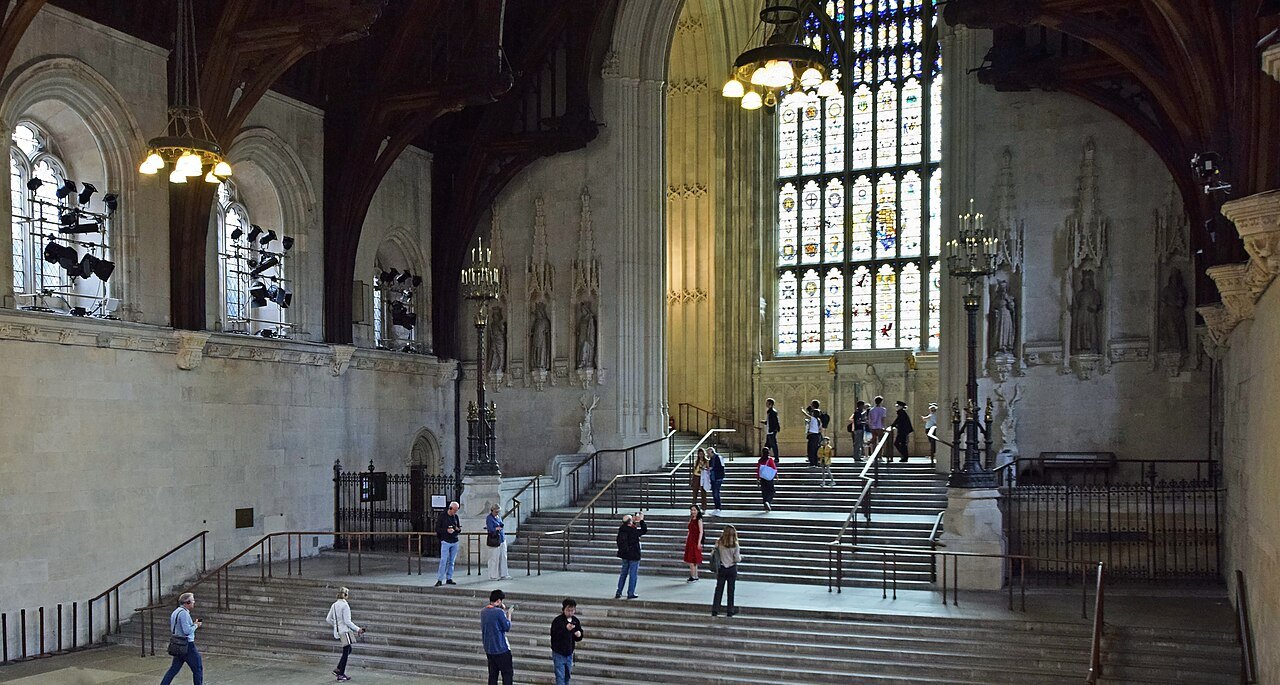 Visitors on the broad steps inside Westminster Hall, under a Gothic window