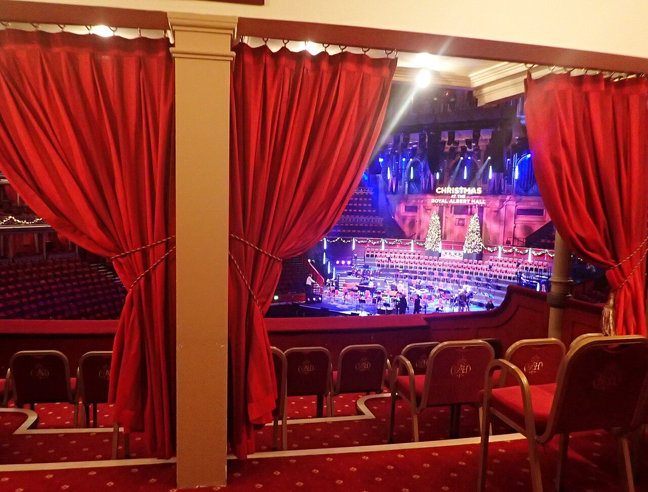 The view through red curtains from a box at the Royal Albert Hall to the stage during a concert