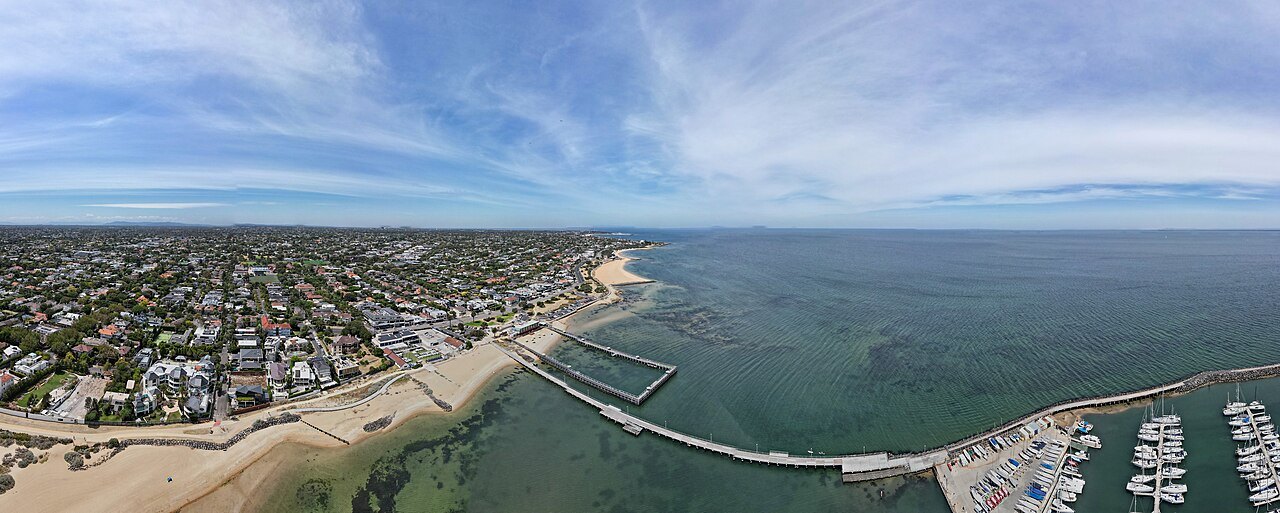 An aerial view of Brighton's coast, a pier reaching into a calm sea beside a seafront of houses