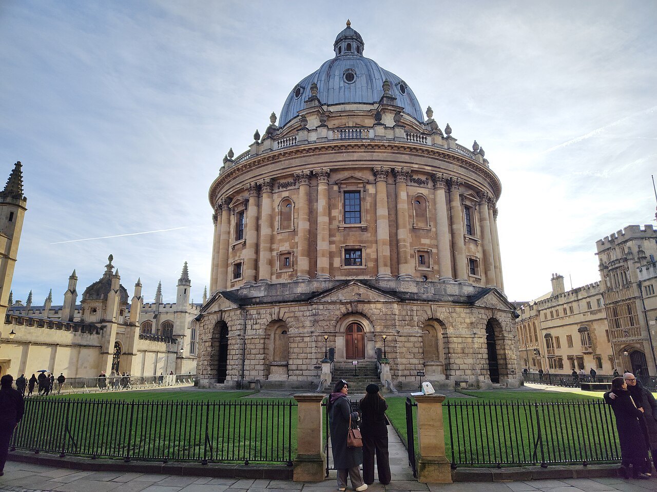 The Radcliffe Camera in Oxford, a round domed library behind railings, with spires of the colleges around it