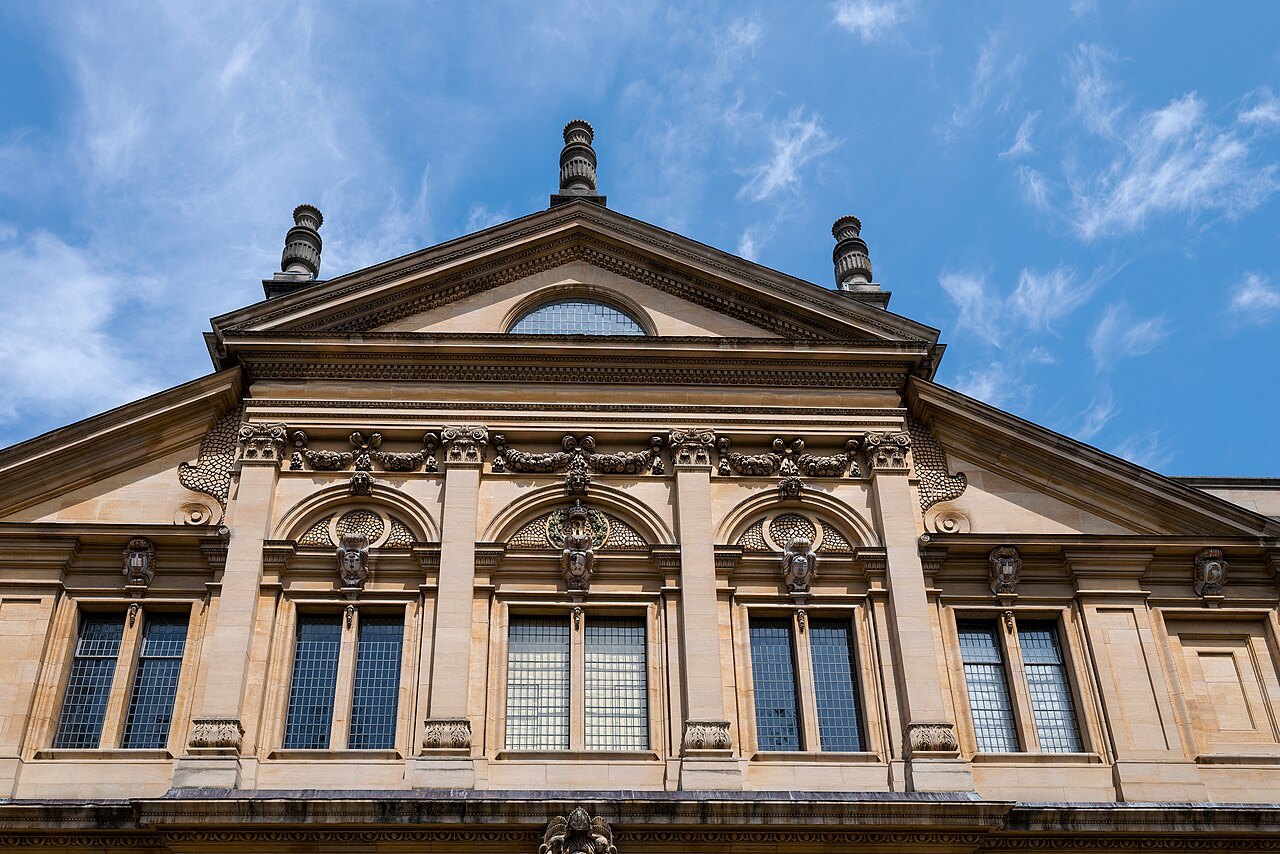 The pedimented front of the Sheldonian Theatre in Oxford, with arched windows and carved heads
