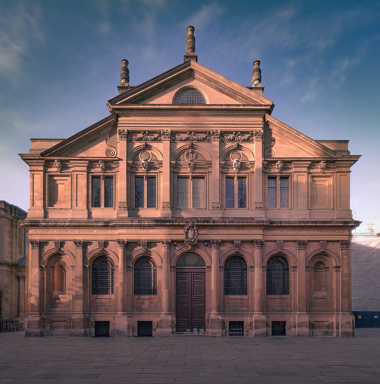 The pink stone front of the Sheldonian Theatre in Oxford, with arched windows and a pediment