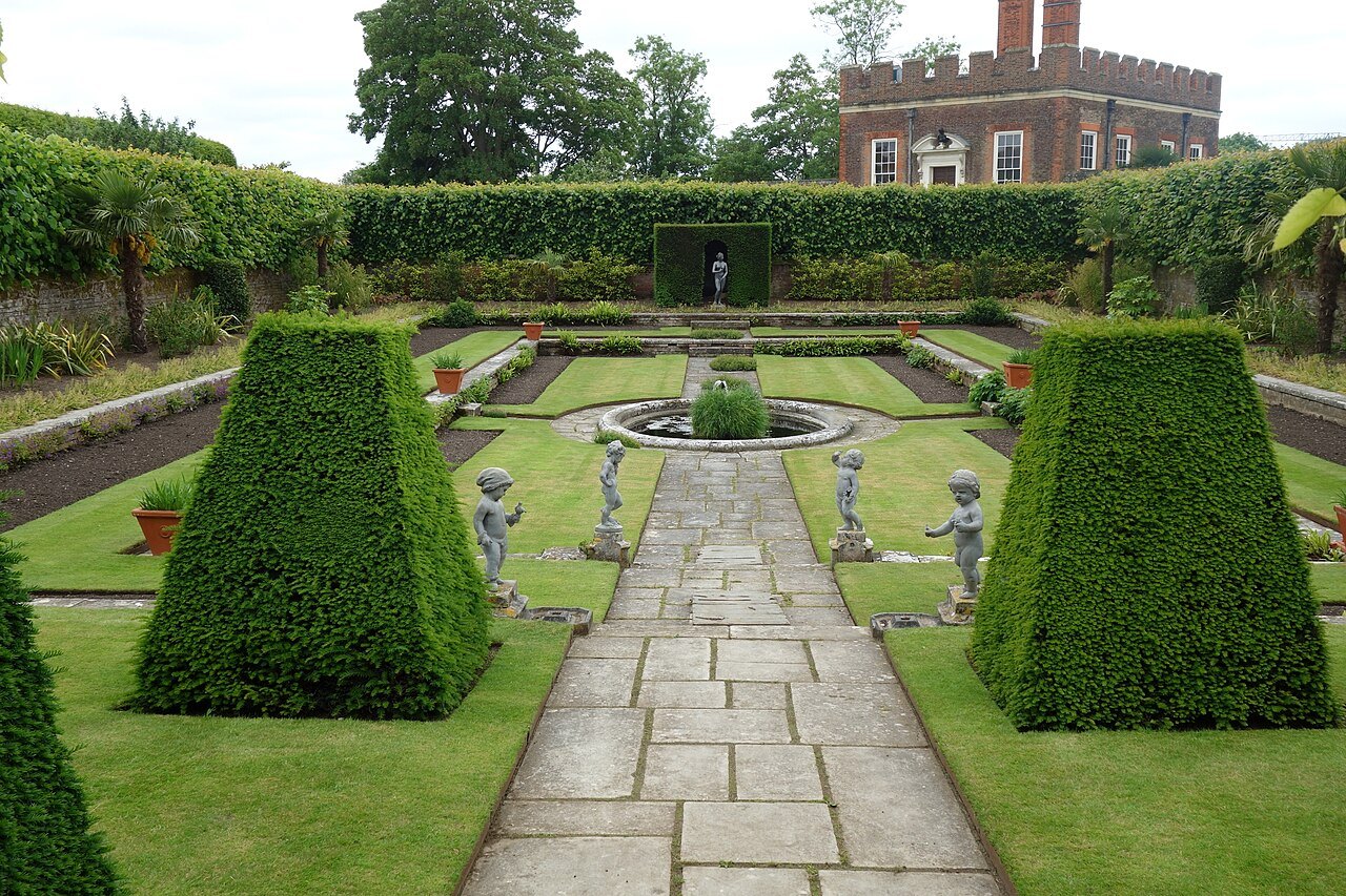 The Privy Garden at Hampton Court Palace, a paved path between clipped hedges with statues beyond