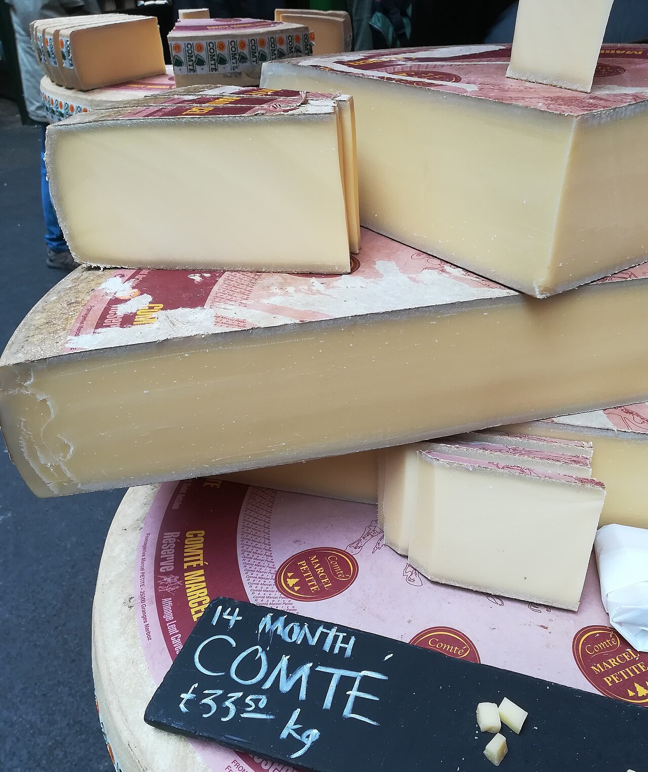 Wedges of Comte and other cheeses, one marked with a slate label, at a Borough Market stall