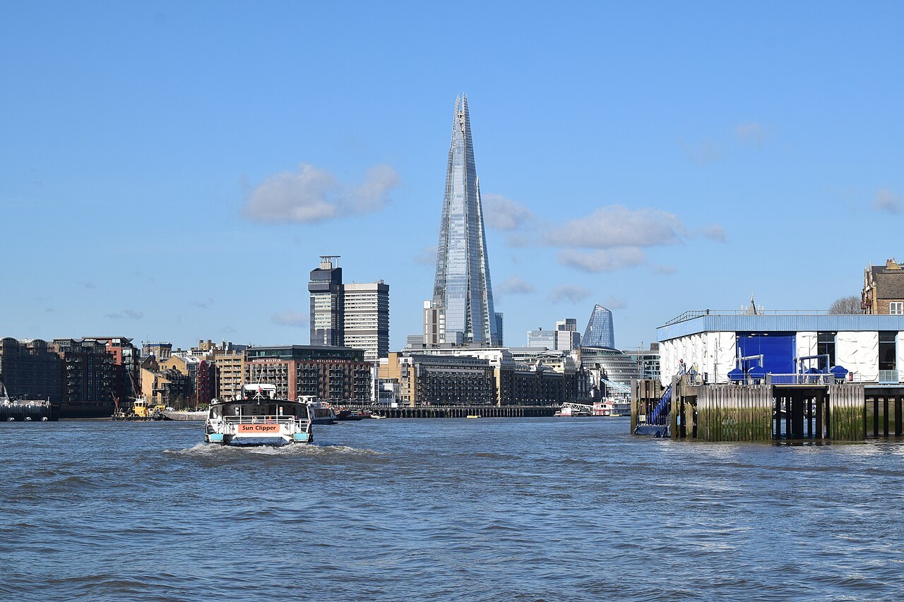 The Shard and a passenger boat on the Thames, with a hospital tower beside it