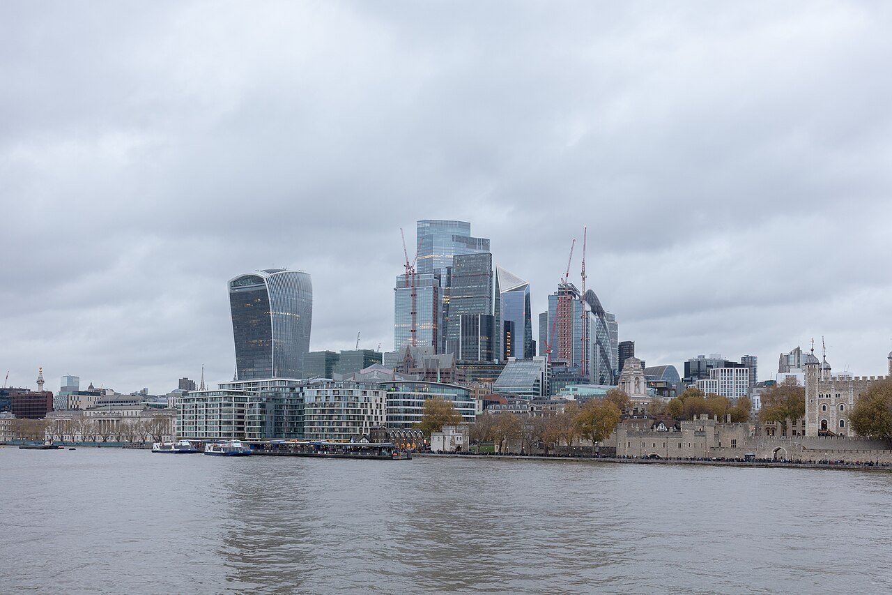 The City's towers and the Tower of London across the river from the south bank, under a grey sky