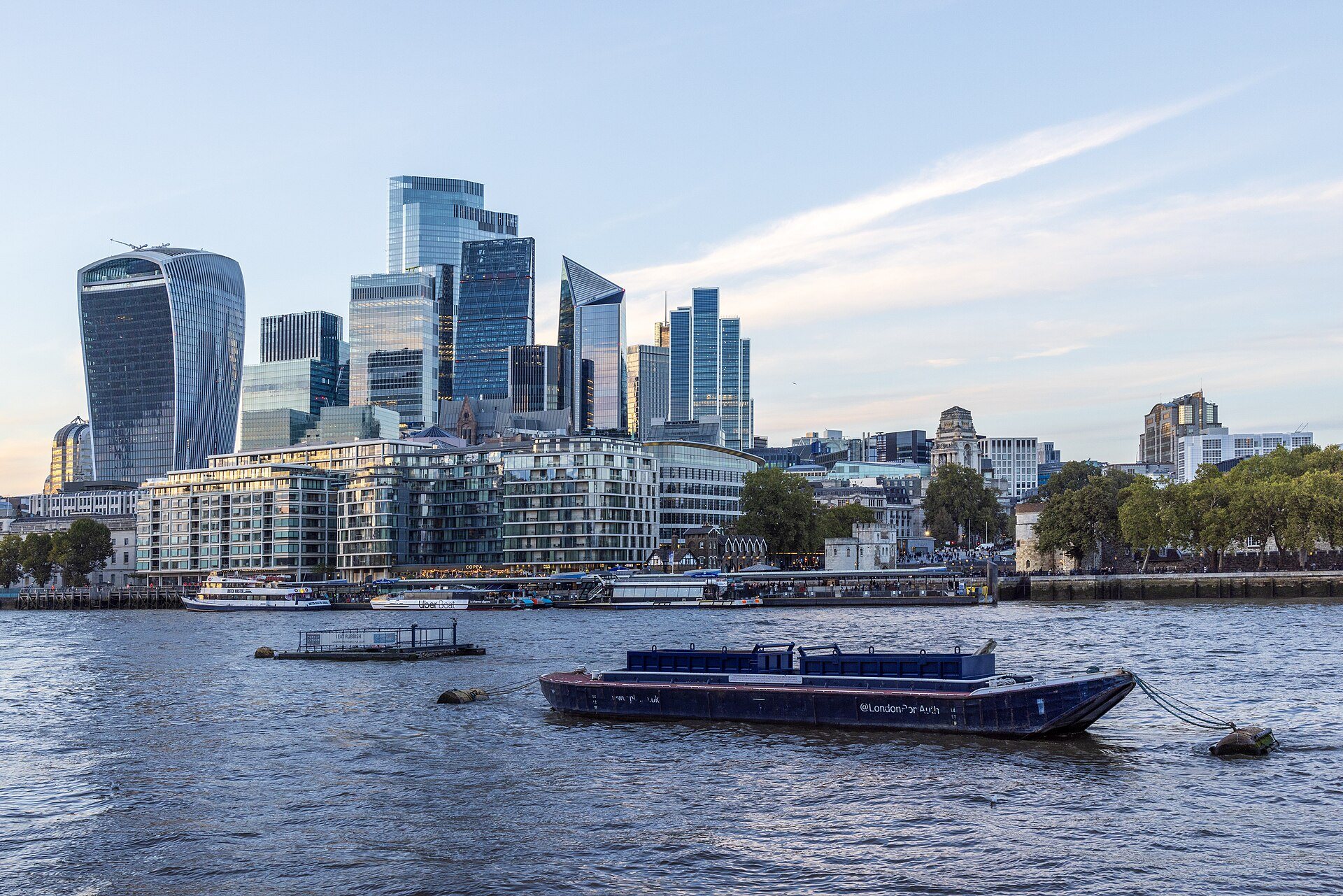 The towers of the City across the Thames, with a moored barge in the foreground