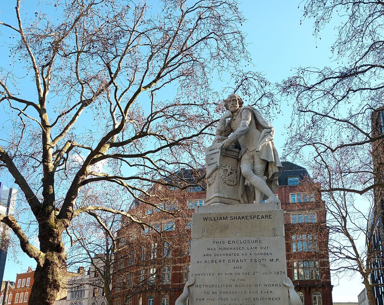 The statue of William Shakespeare in Leicester Square, with bare plane trees and a red brick building behind