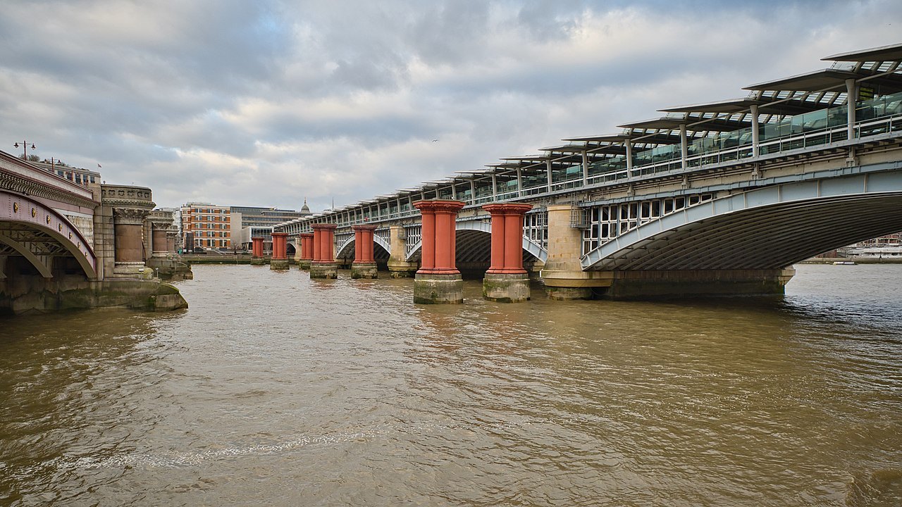 Blackfriars Railway Bridge and the old red piers beside it, over the brown Thames