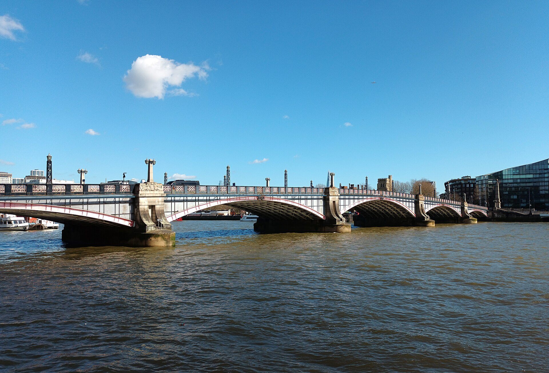 Lambeth Bridge crossing the Thames on its low arches, with a clear blue sky