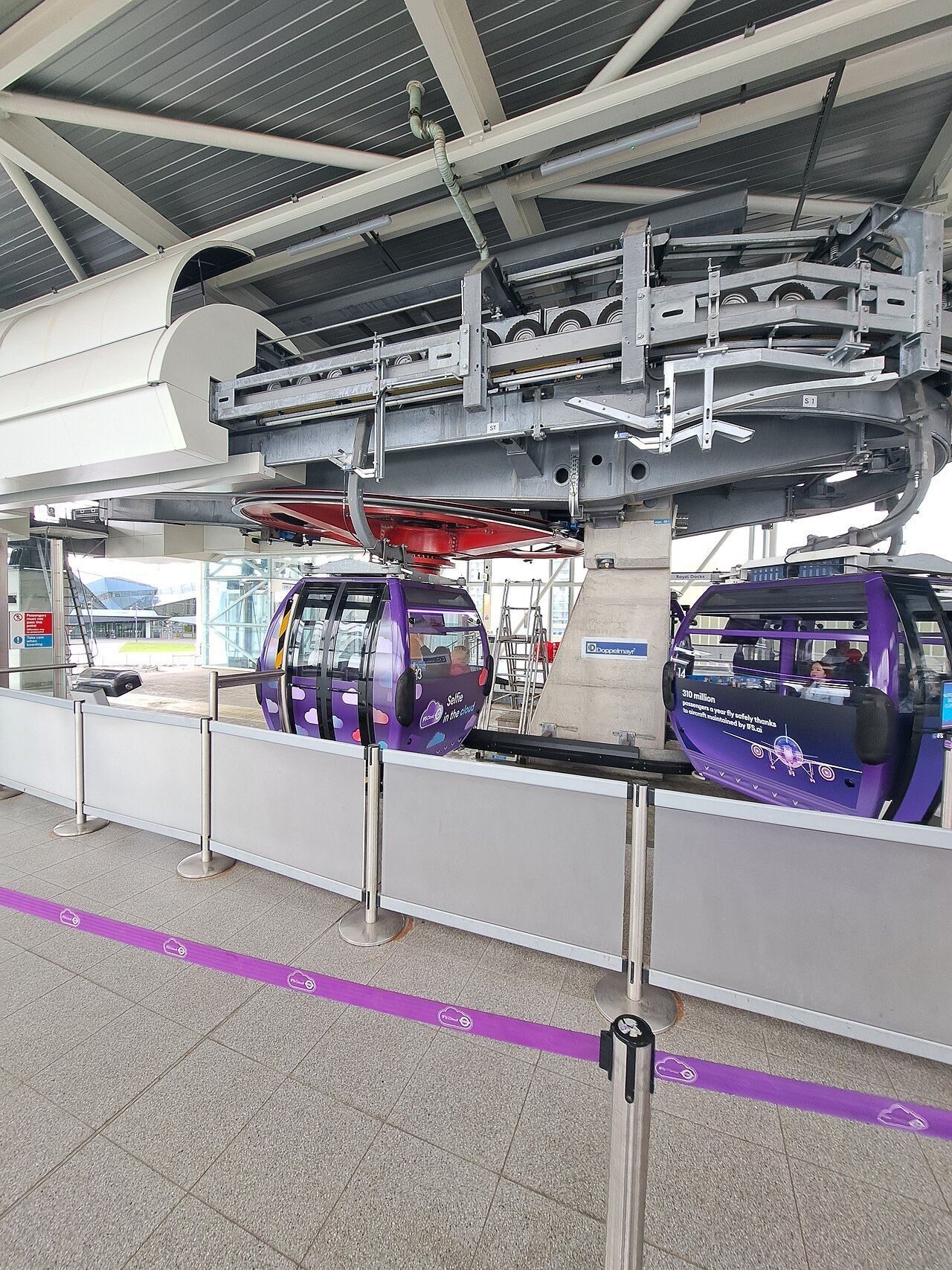 The cabins of the cable car at its station on the Greenwich peninsula, with purple gondolas waiting