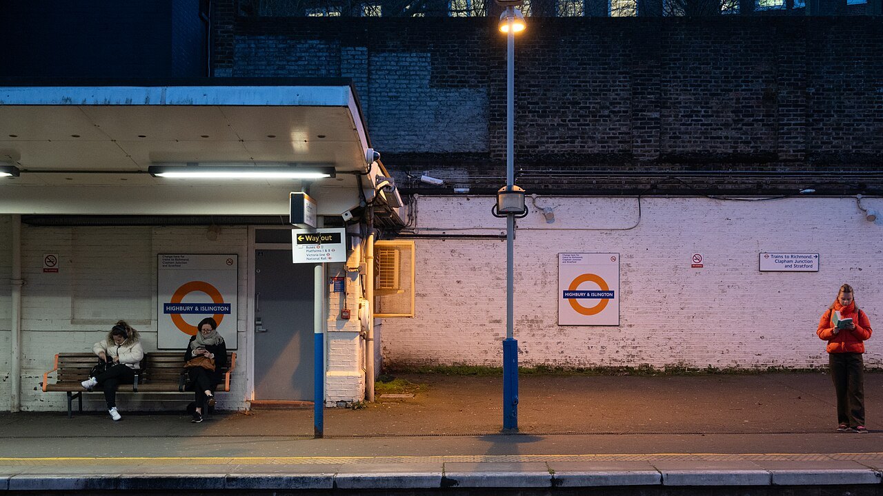 A quiet platform at Highbury and Islington station in the evening, with a bench and lamps