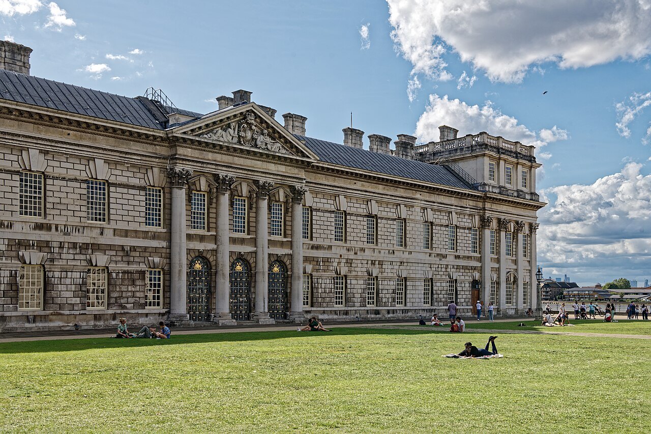 The weathered stone of King Charles Court, one block of the Old Royal Naval College, with people on the lawn