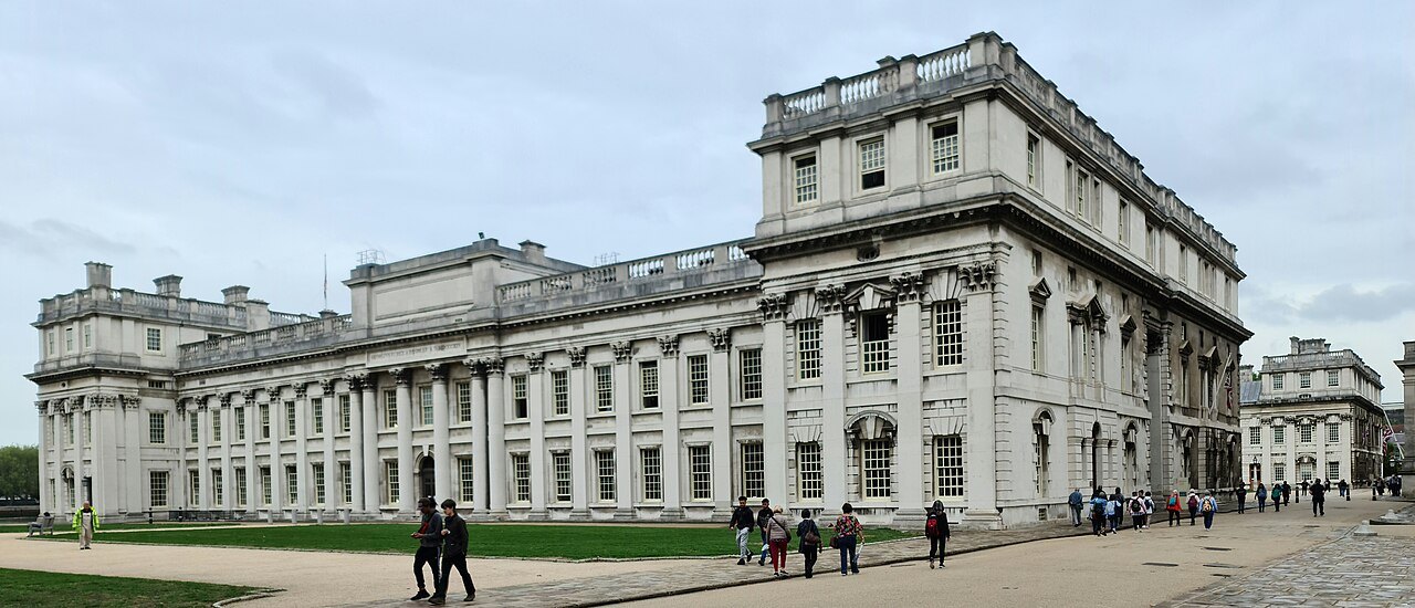 The long colonnaded front of the Old Royal Naval College in Greenwich, with visitors walking past