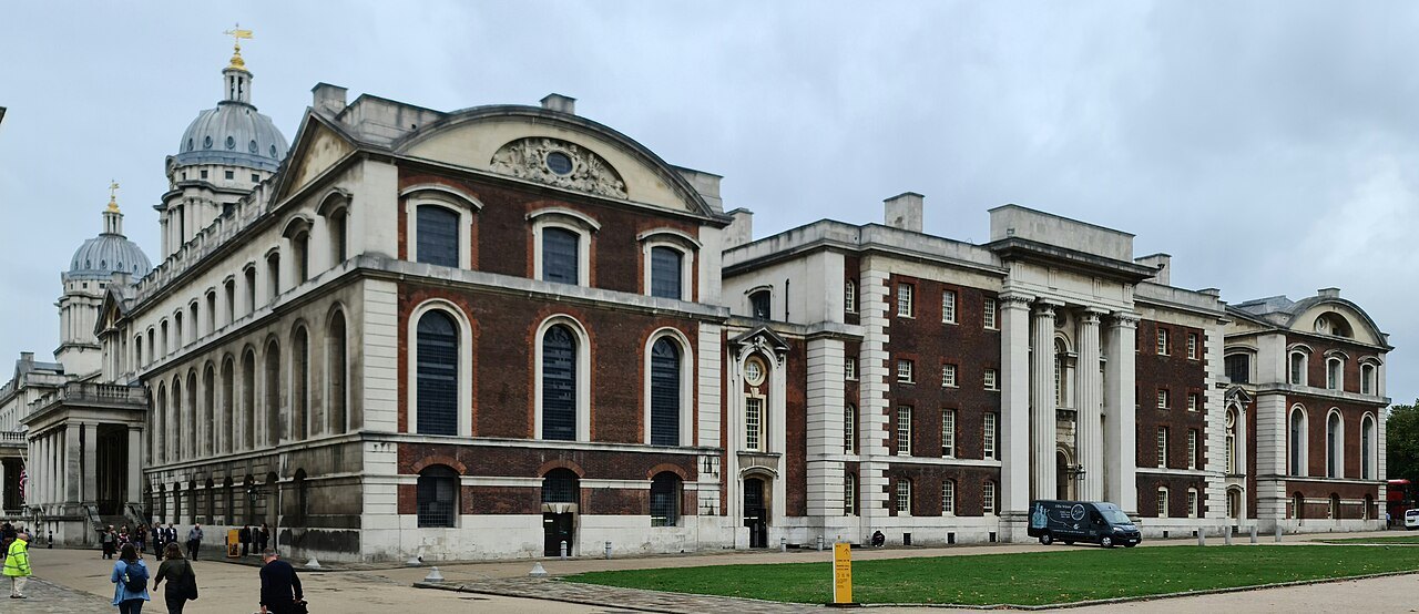 The brick and stone front of a block of the Old Royal Naval College, with a dome behind it