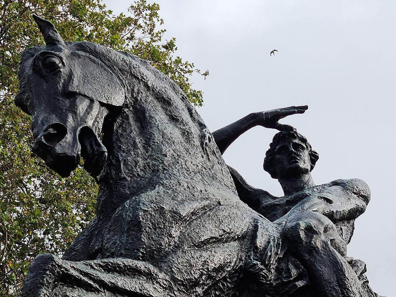 The bronze horse and rider of Physical Energy in Kensington Gardens, seen from below against the sky