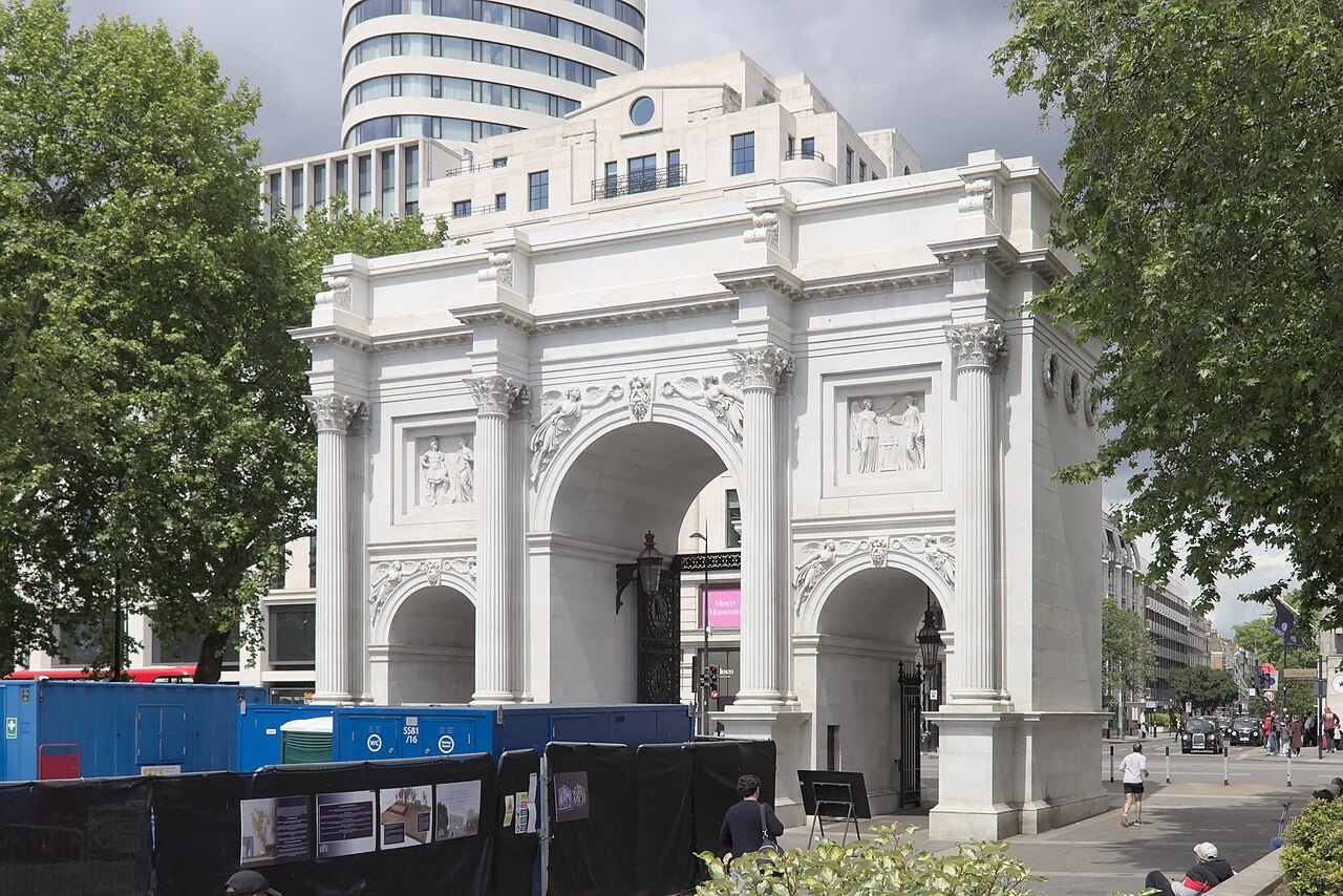 The white marble front of Marble Arch with cranes and hoardings beside it