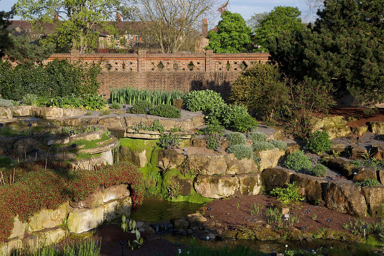Kew's rock garden, with stone terraces and plants below a brick wall