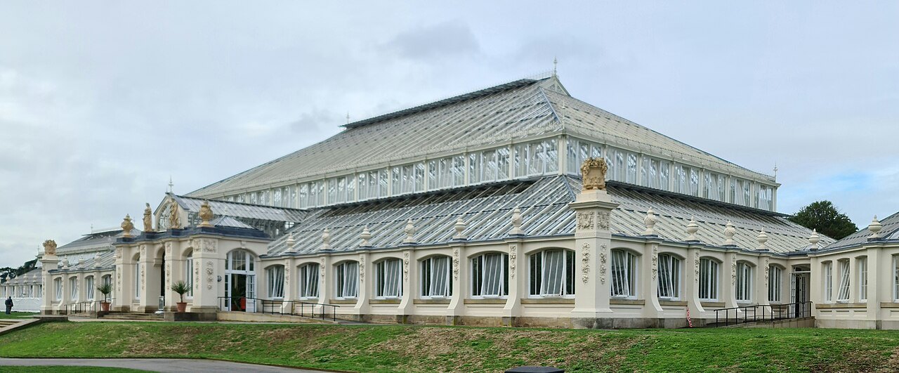 The long white front of the Temperate House at Kew, its glass roof stepped above the arched windows