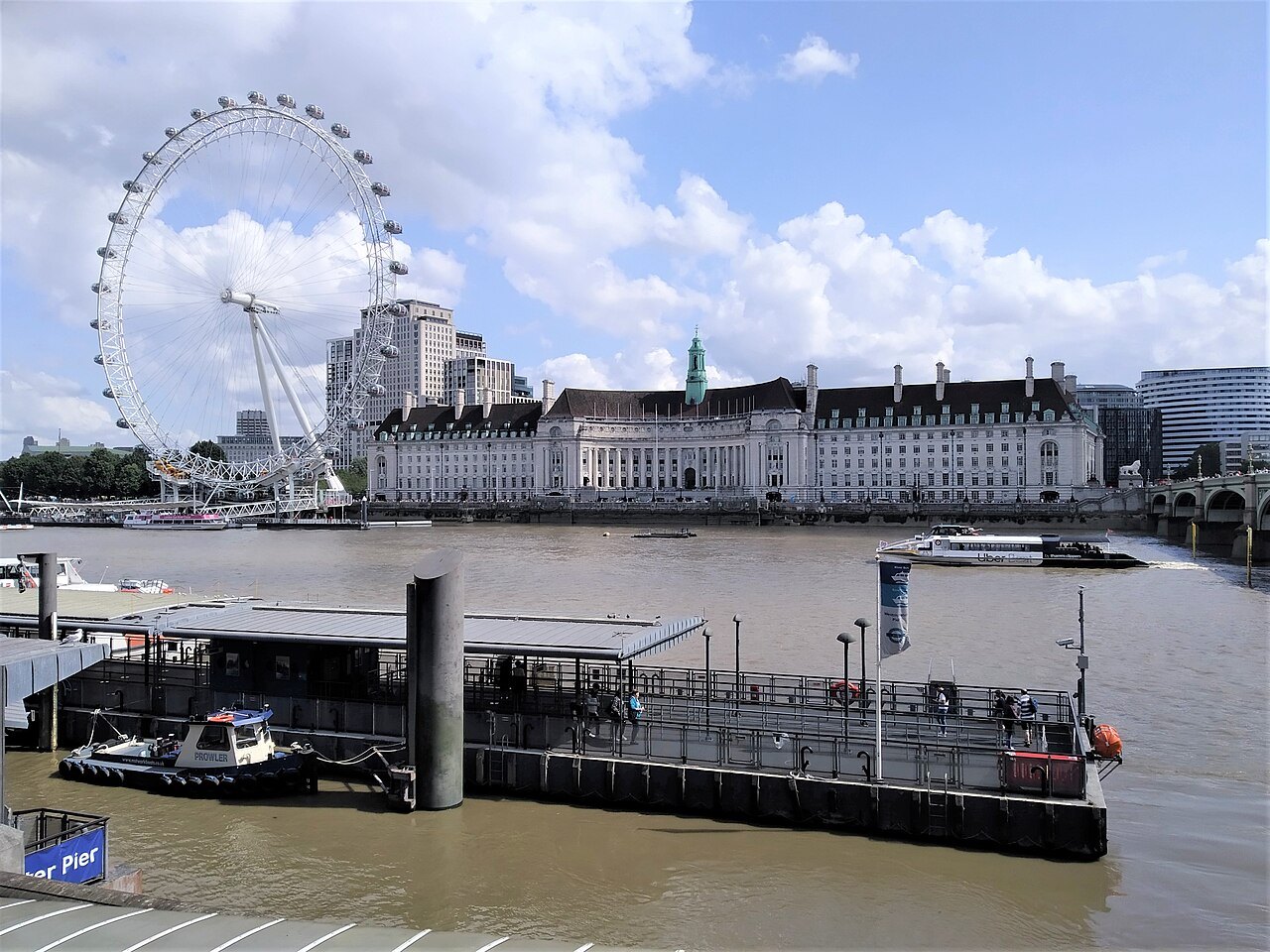 The London Eye and County Hall beyond a river pier on the Thames