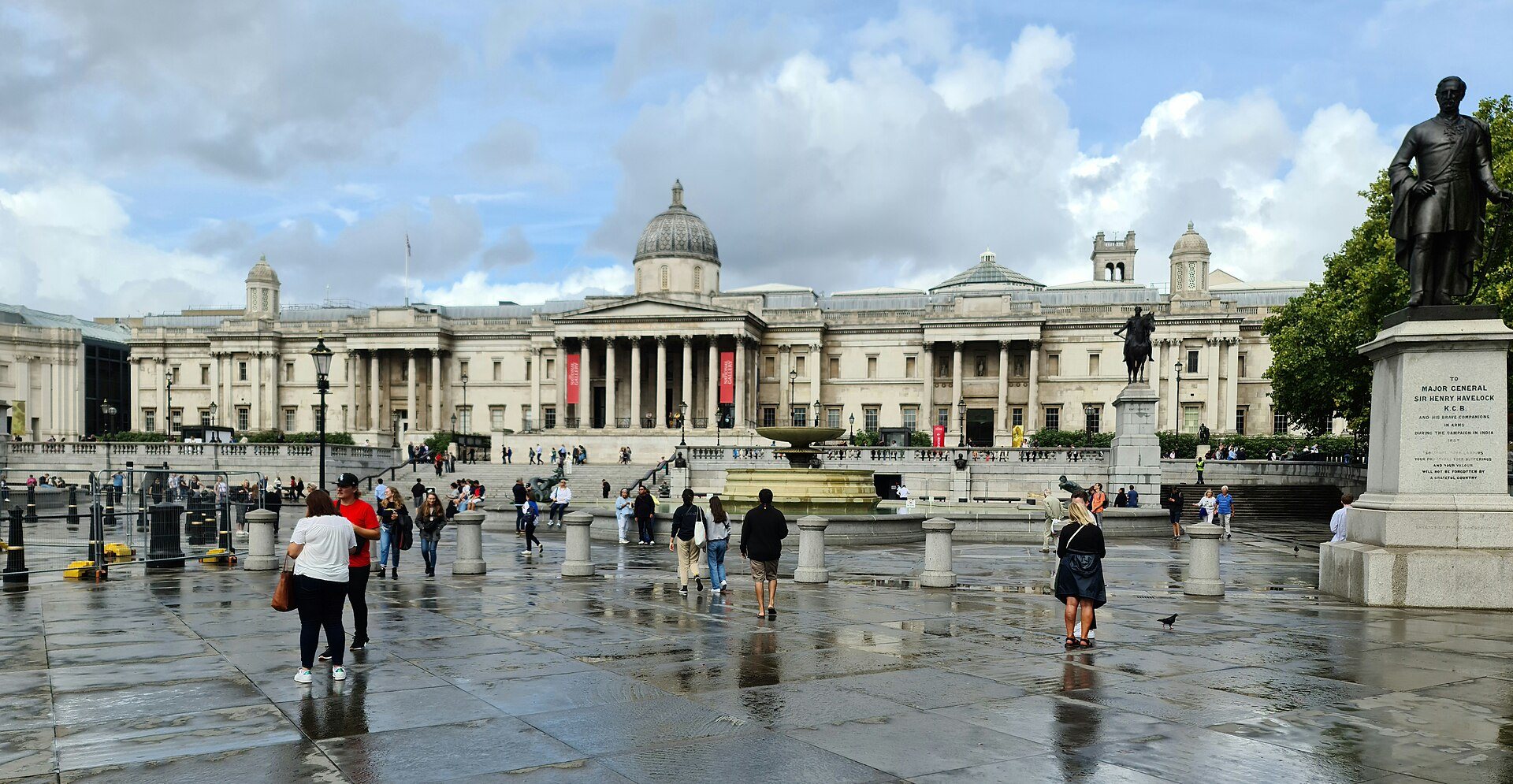 The portico of the National Gallery across Trafalgar Square on a wet day, with the Nelson's Column area at the right
