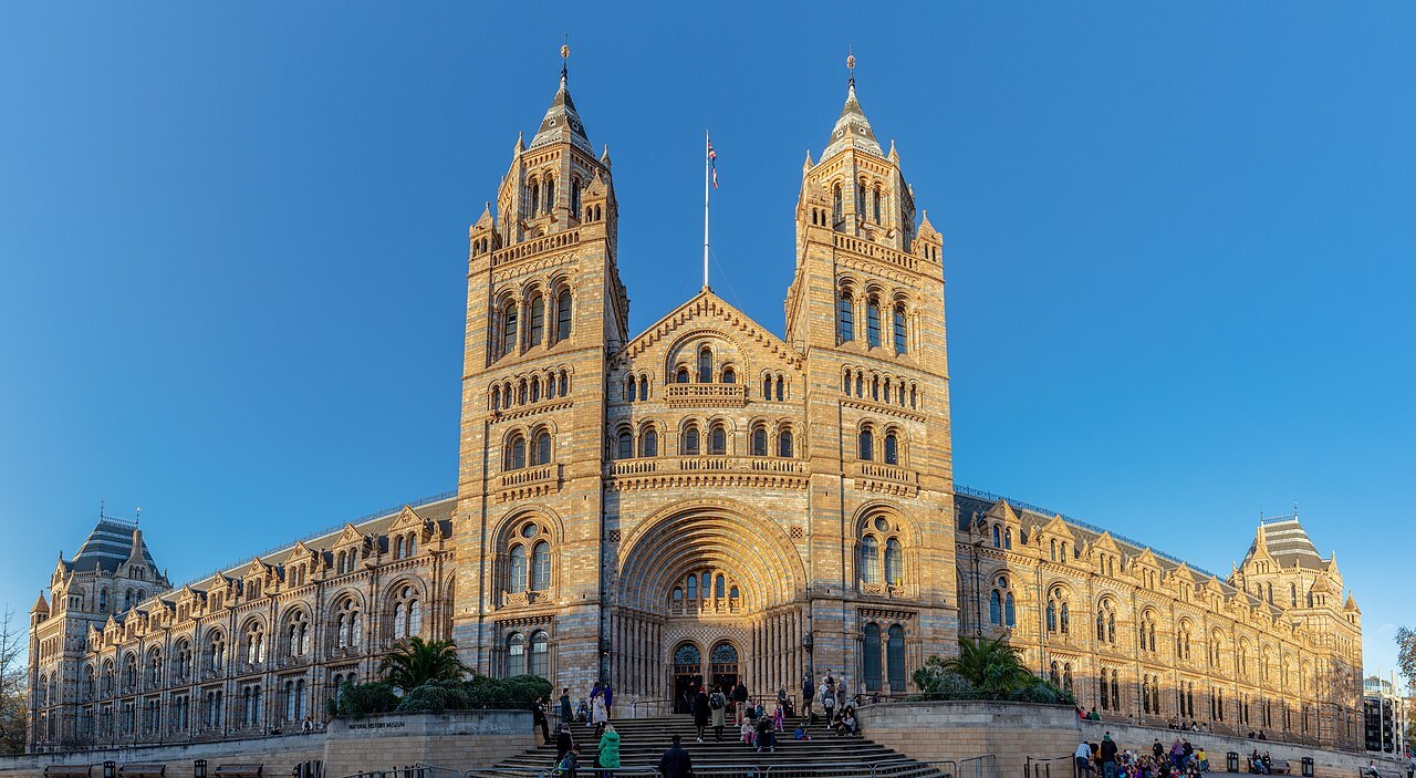 The Natural History Museum's front lit by low sun, seen from the street with its two towers