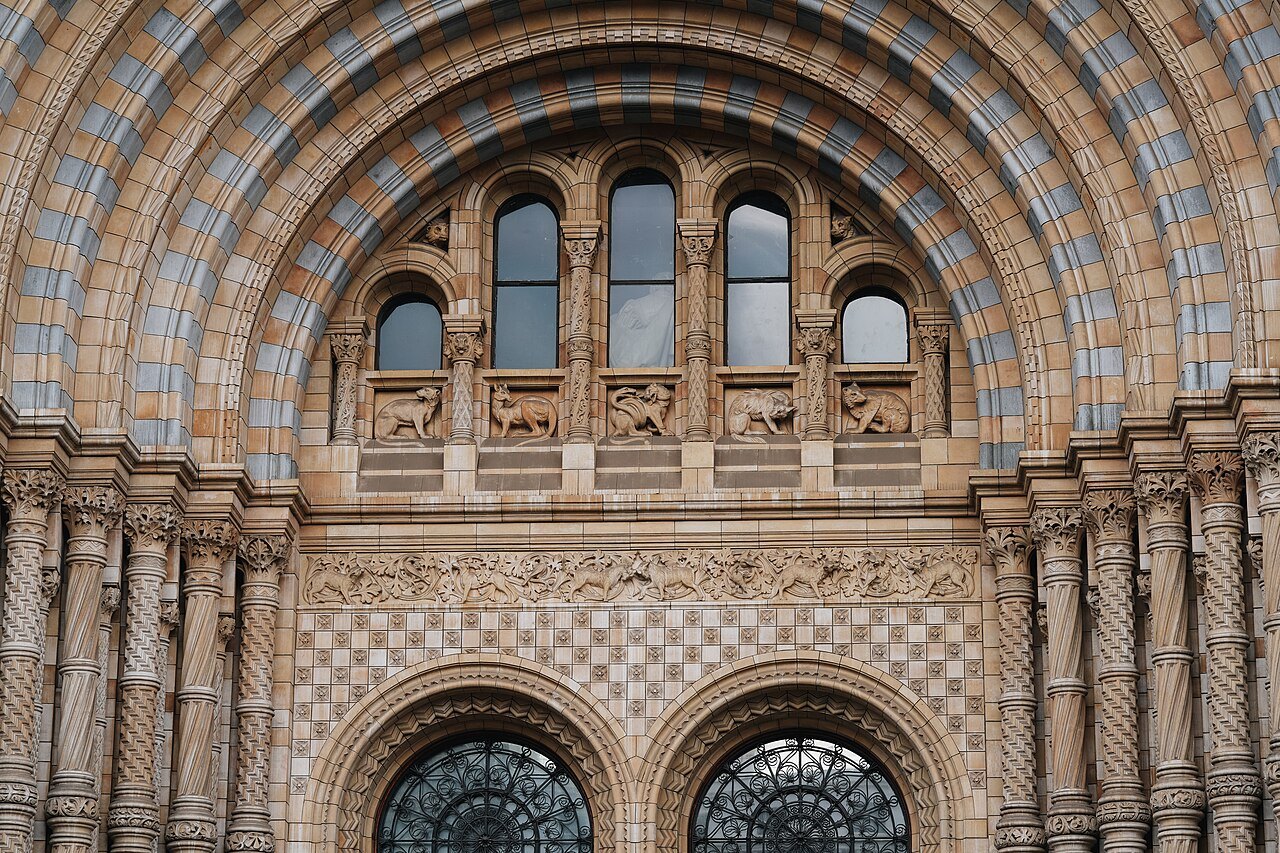 The great arched doorway of the Natural History Museum, banded in blue and cream terracotta with carved ornament