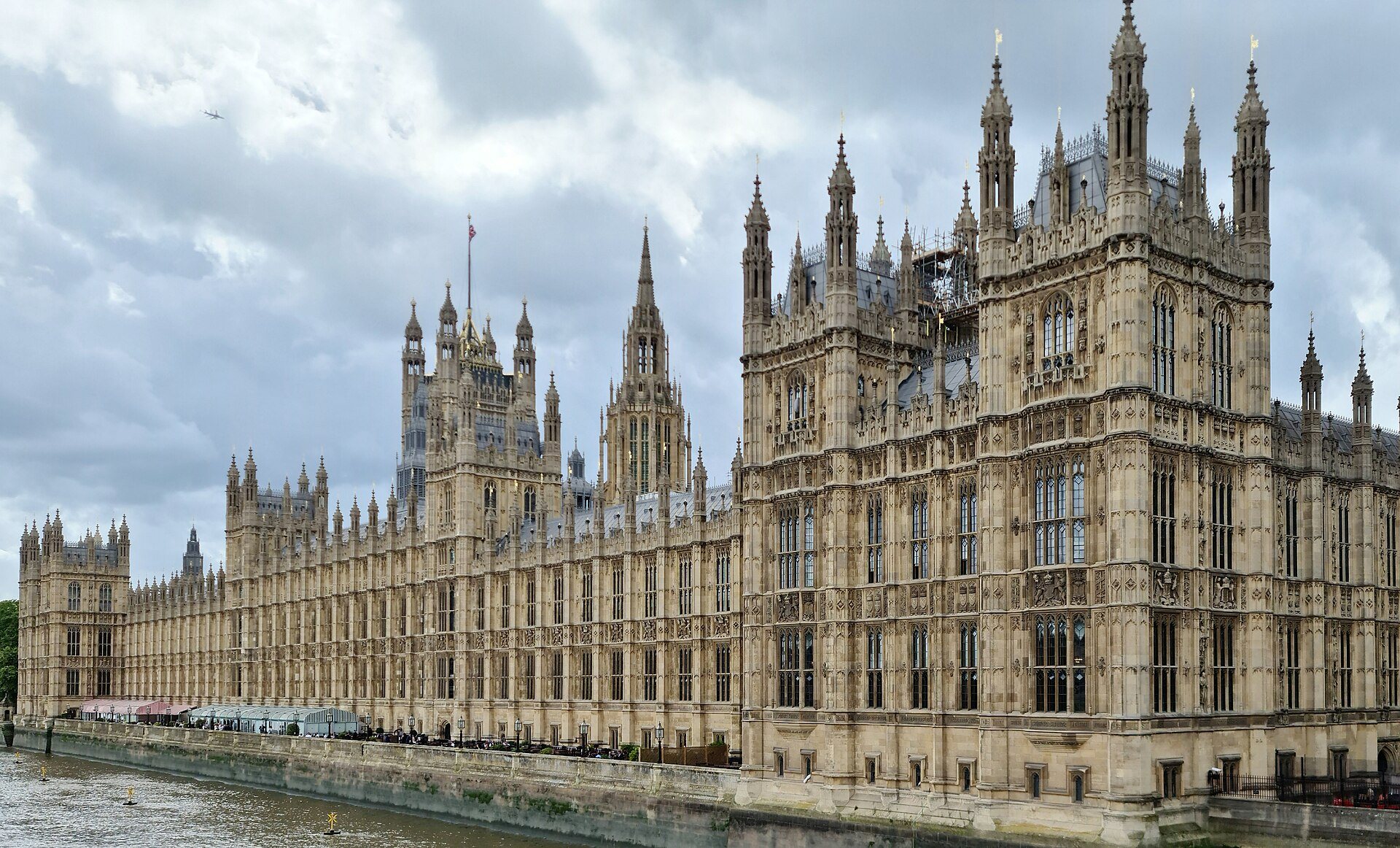 The long river front of the Palace of Westminster under a cloudy sky