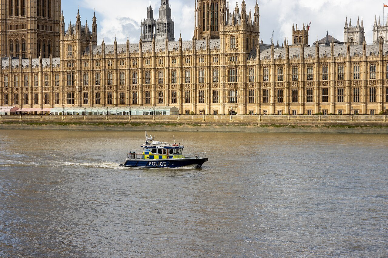 The palace's long river front with a police launch crossing the Thames in front of it
