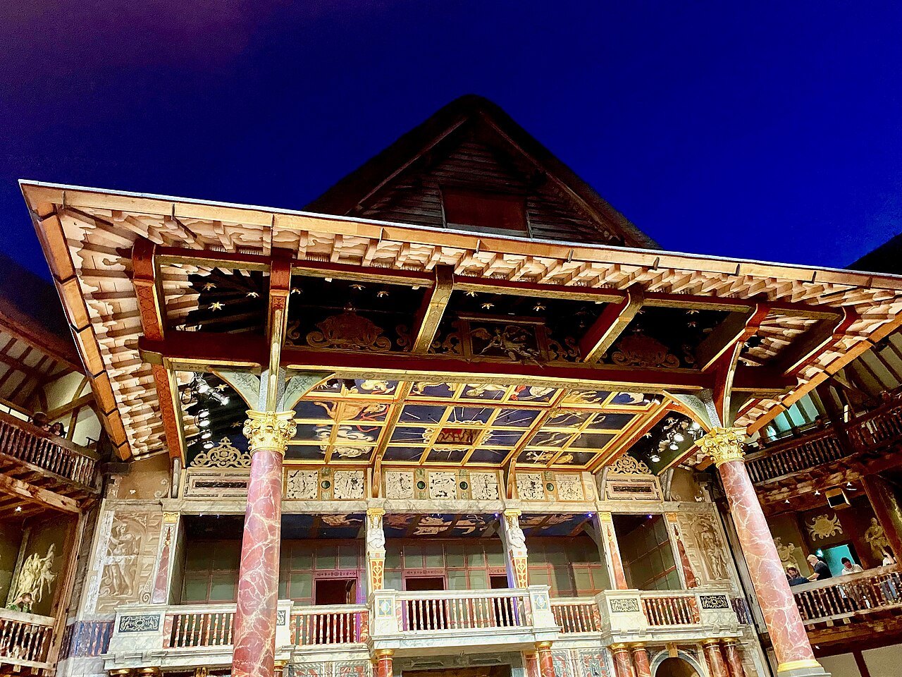 The painted and gilded canopy of the stage at Shakespeare's Globe, lit against the night sky