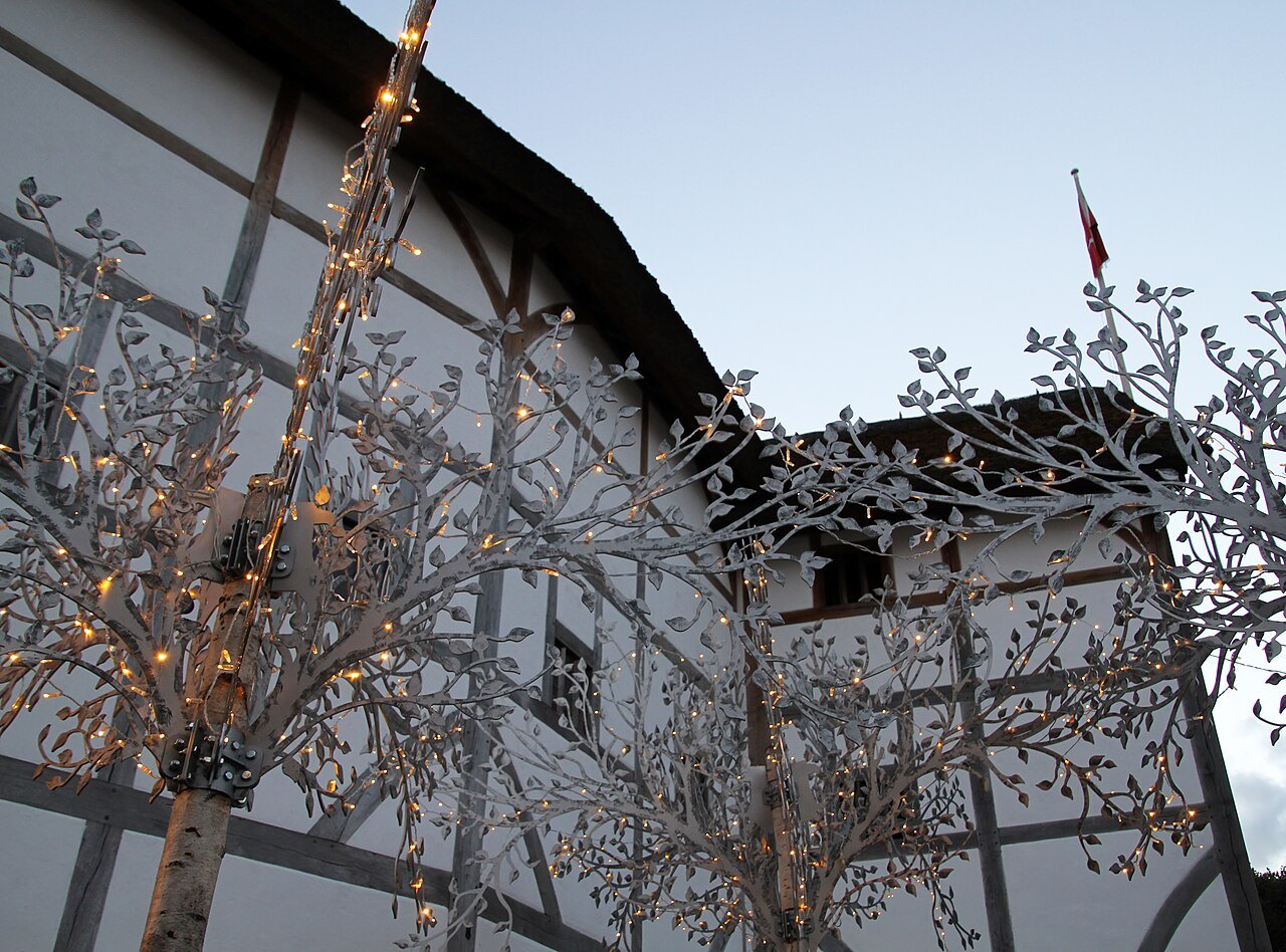 Fairy lights in a bare tree in front of the timber and plaster wall of Shakespeare's Globe