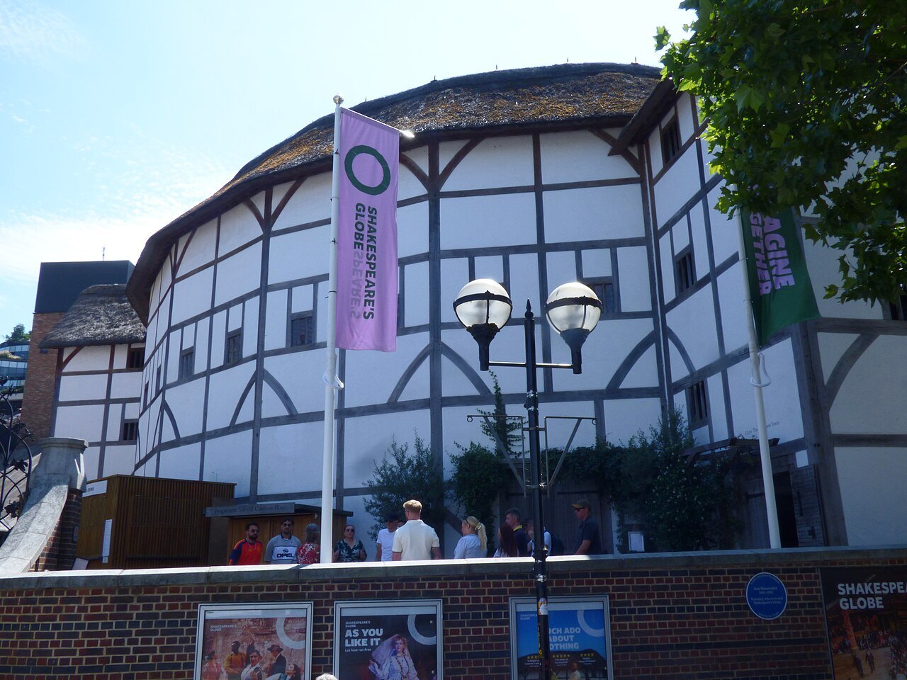 The Globe's timber frame and thatch against a grey sky, with a purple banner on a flagpole