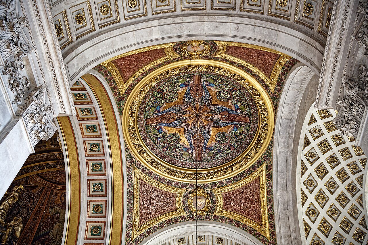A mosaic ceiling in a side aisle of St Paul's, in gold, red and blue, with a panelled arch beside it