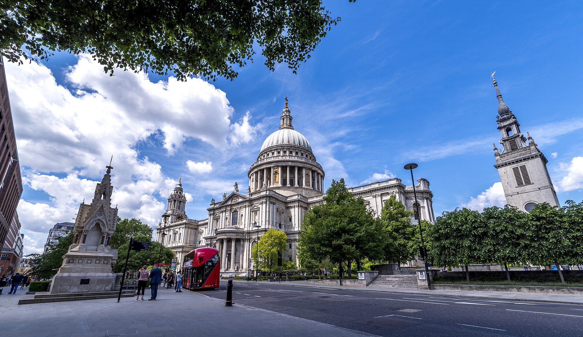 St Paul's Cathedral at the end of a quiet street, with a red bus passing and the tower of another church at the right