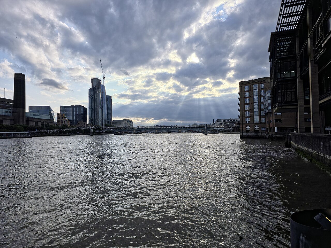 Evening light breaking through cloud over the Thames, seen with Tate Modern's chimney at the far end of the river